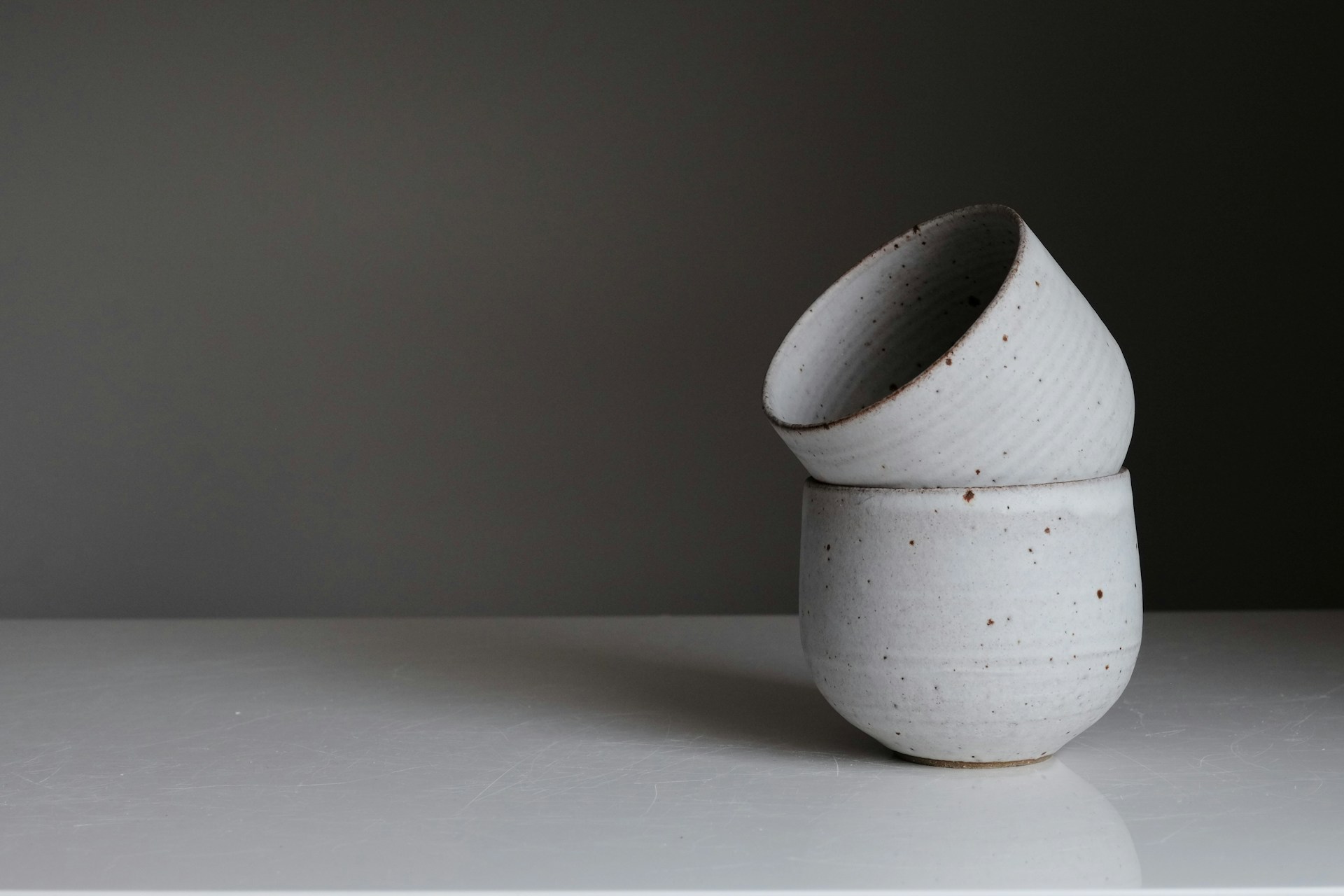 Two handmade speckled ceramic vessels, photographed in natural light