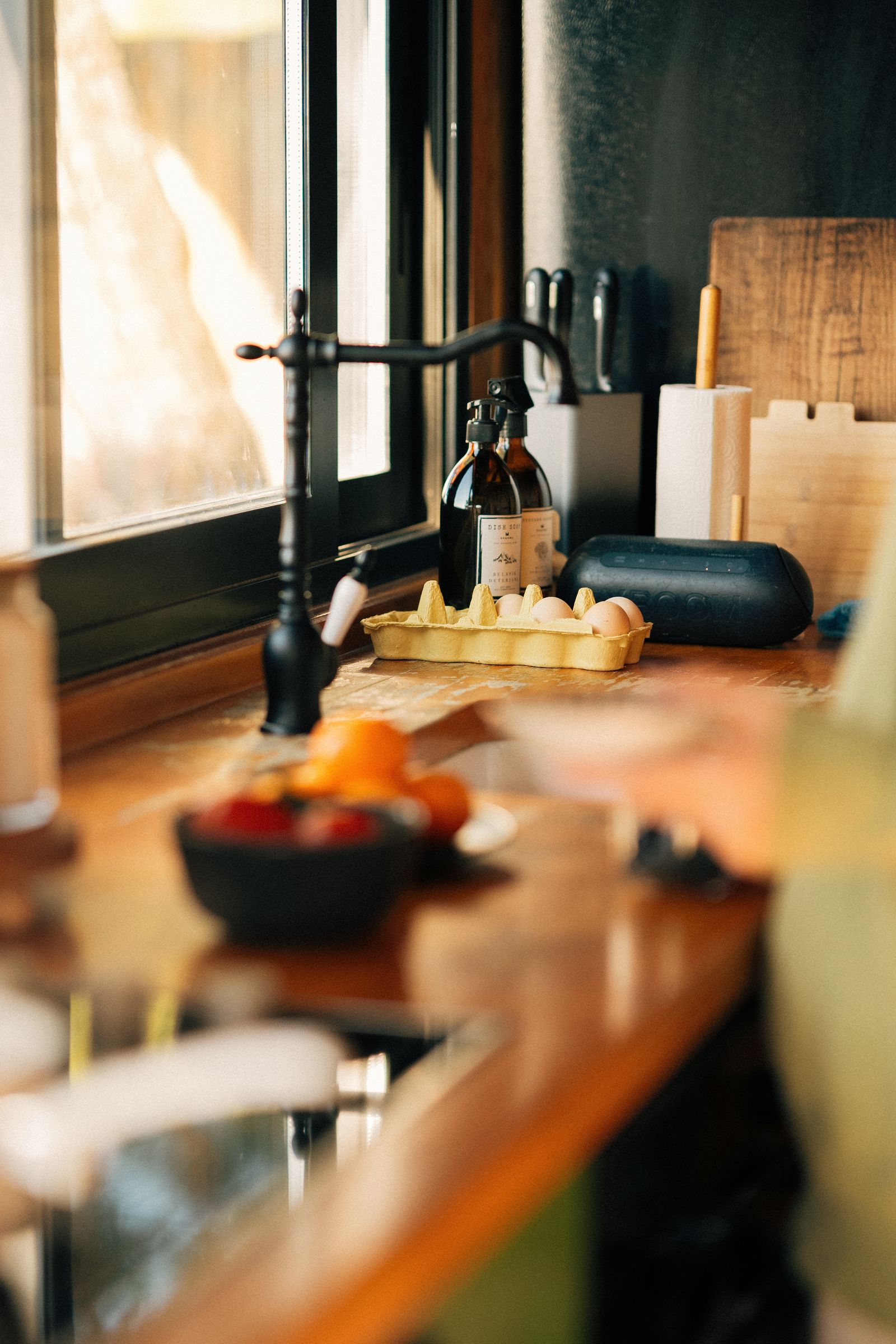 A sunlit kitchen counter with eggs and oranges in warm morning light